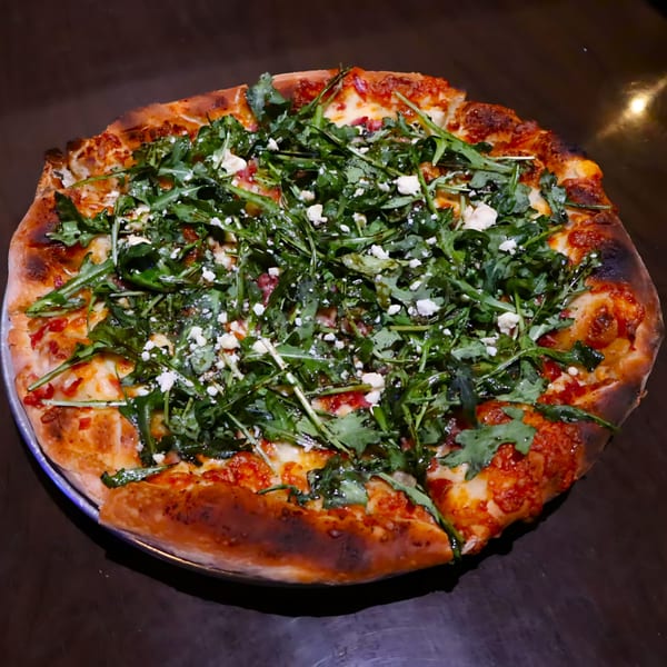 Casey's Drexel Hill pizza, topped with fresh arugula, crumbled feta cheese, and tomato sauce.