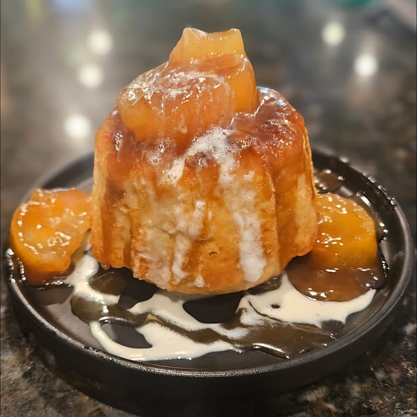 A warm apple dumpling dessert with caramel and cream drizzle on a dark plate at Casey's Drexel Hill.