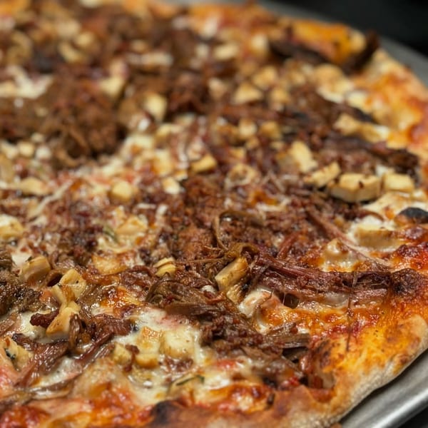 Close-up of a Casey's Drexel Hill pizza topped with shredded meat, cheese, and mushrooms.